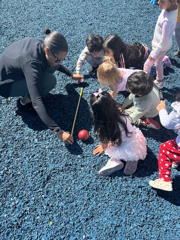 Teacher and children engaged in outdoor play at Adventure Montessori Academy